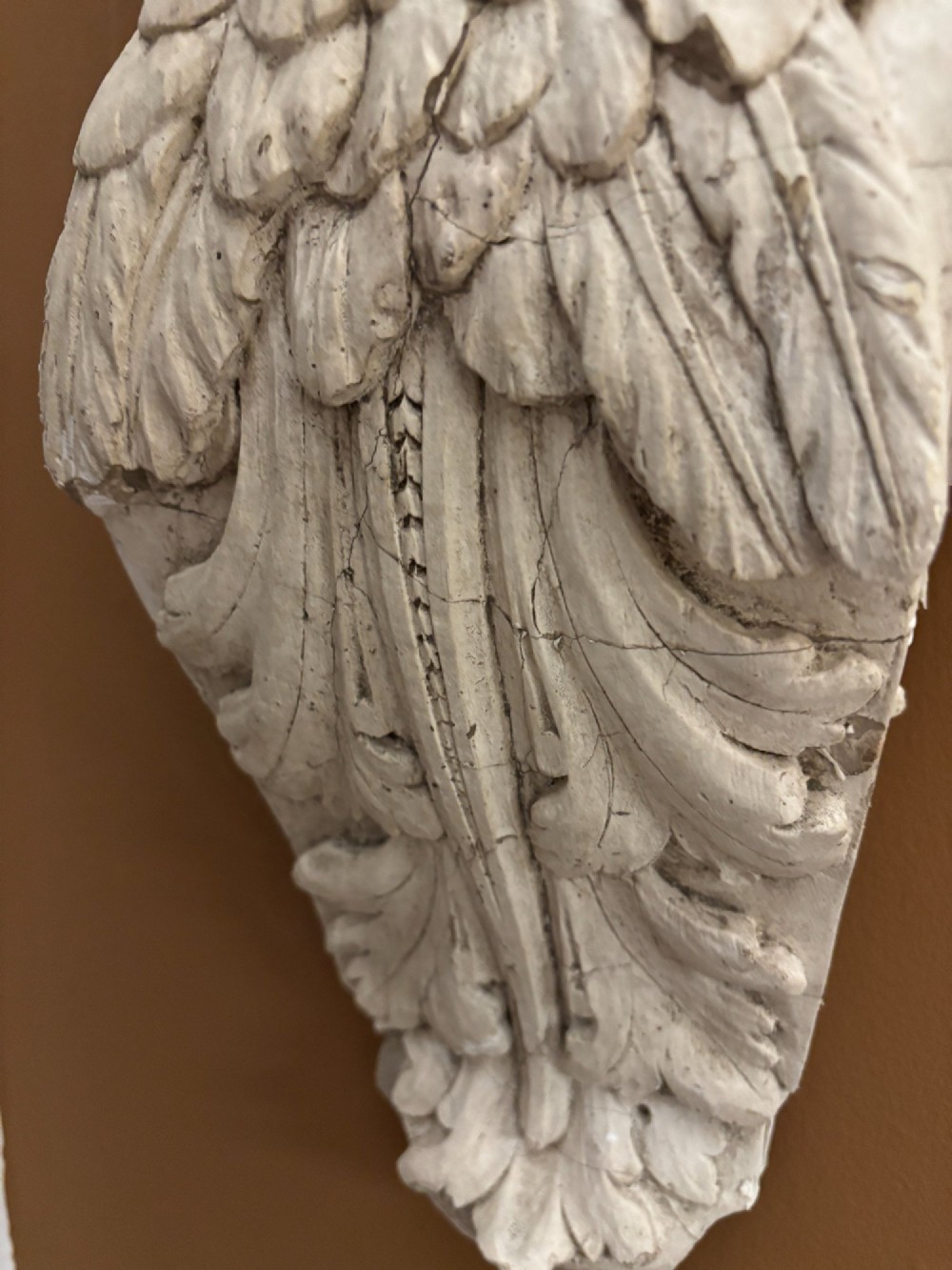A 19th-century carved off-white architectural wall corbel featuring a winged putto head above acanthus leaf details. View IV