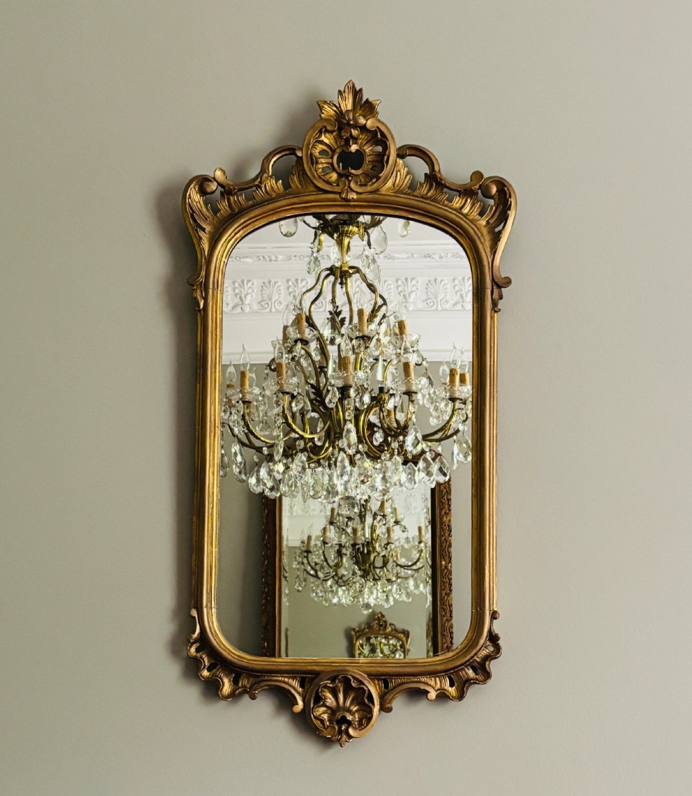 A tall French giltwood pier mirror featuring an ornate carved shell motif crest, decorative scrollwork frame, and gold leaf finish. View III