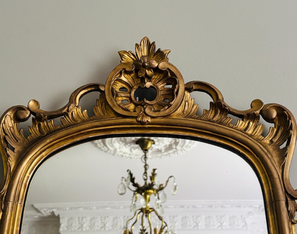 A tall French giltwood pier mirror featuring an ornate carved shell motif crest, decorative scrollwork frame, and gold leaf finish. View II