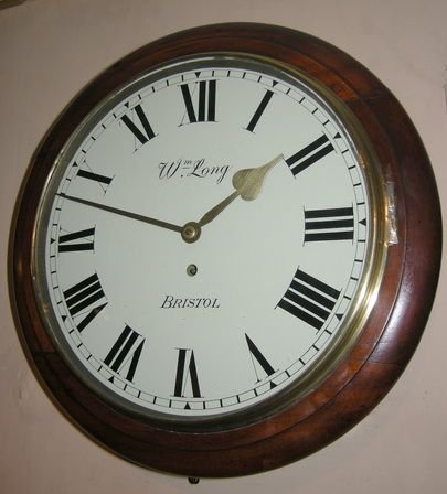 An English Fusee Dial Clock. A Mahogany Case with a Brass Bezel Surround. A 12" Painted Dial with Rarer Feature of Brass Hands. An 8-Day Duration Timepiece Fusee Mechanism. 

William Long of Bristol Is Recorded in a J Moores 'The Clockmakers of Bristol' Book as Working from 1884-1889. 

Overall Width 15" / 38cms