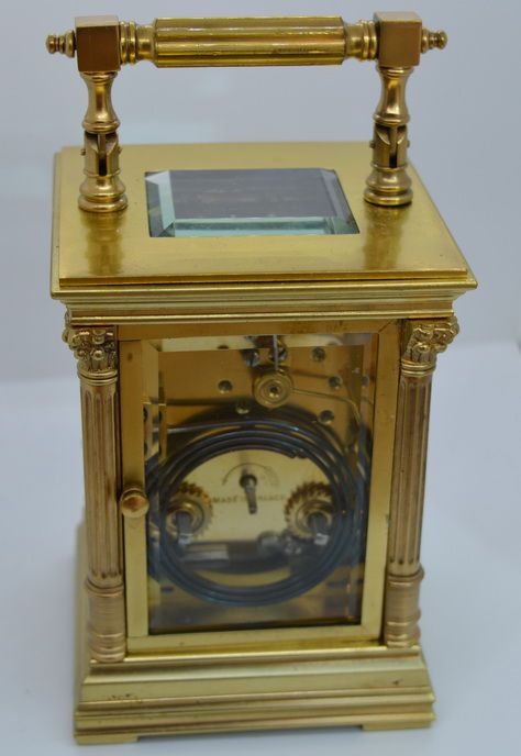 fig 1. A gilt brass French carriage clock featuring fluted Corinthian corner columns, bevelled glass panels, and a white enamel dial with Roman numerals.