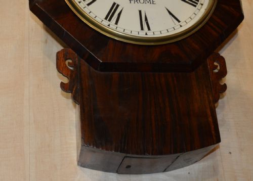 fig 1. A Victorian drop dial fusee wall clock with an octagonal mahogany frame, cream dial face, black Roman numerals, and carved side ears.