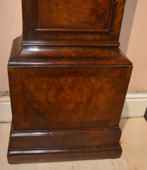 fig 1. An 18th-century Georgian burr walnut longcase clock featuring an arched hood with side columns and a brass dial with silvered chapter ring.