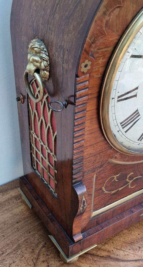 fig 2. An arched rosewood bracket clock with brass floral inlay, white circular dial signed S. Simpson Southampton with Roman numerals, and side drop handles.