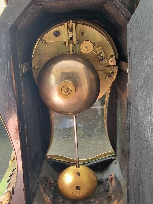 fig 1. An ornate French Rococo style mantel clock featuring brass and red tortoiseshell Boulle marquetry, gilded ormolu mounts, and a dial with blue Roman numerals on white enamel cartouches.