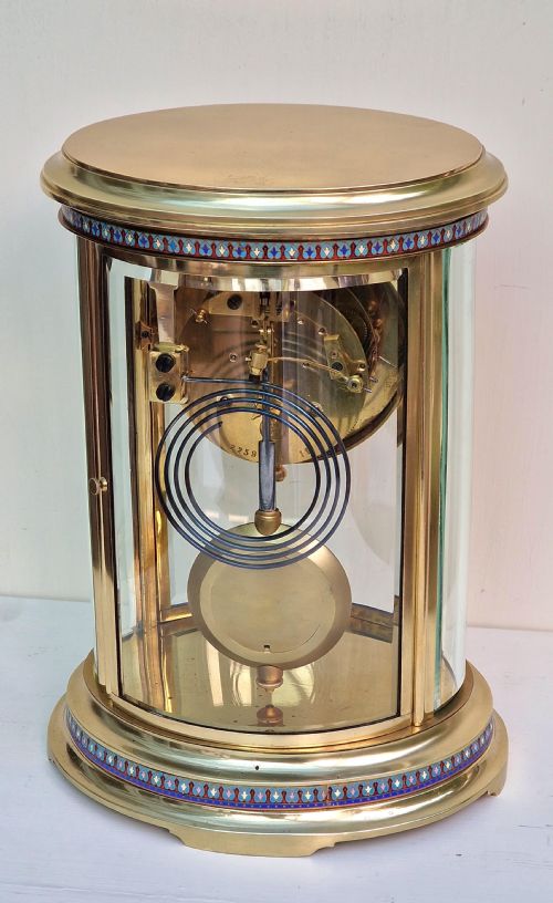 fig 1. An antique oval brass four-glass mantel clock featuring enamel borders and a jewel-encrusted dial.