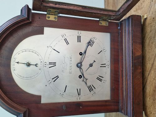 fig 1. A Georgian mahogany bracket clock featuring an arched top with a brass carrying handle, silvered engraved dial with Roman numerals, and brass bracket feet.