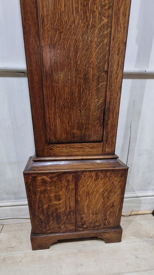 fig 1. A Georgian oak longcase clock featuring a swan-neck pediment with brass eagle finials and an arched brass dial.