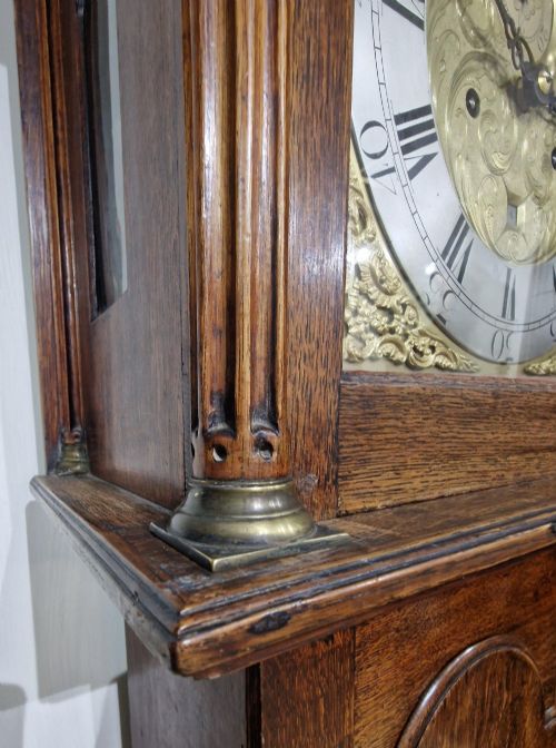 fig 2. A Georgian oak longcase clock featuring a swan-neck pediment with brass eagle finials and an arched brass dial.