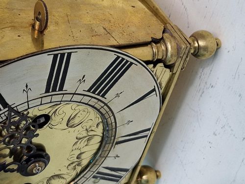 fig 2. A 17th-century English brass lantern clock featuring an overhead bell, decorative pierced frets, ball feet, and an engraved dial centre signed Thomas Langley London.