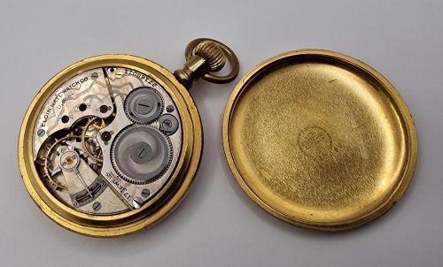 fig 1. An open face Elgin pocket watch with a textured gold-coloured case, white enamel dial, black Roman numerals, steel hands, and a sub-seconds dial.