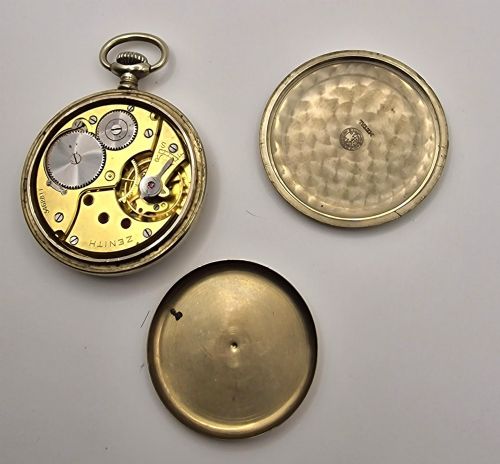 fig 1. A Zenith open-face military pocket watch featuring a black dial, white Arabic numerals, a subsidiary seconds dial, and a silver-tone metal case.