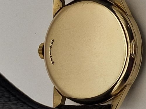fig 1. A 1954 Omega Century wristwatch with a gold-filled circular case, patinated dial with arrow markers, sub-seconds display, and a black leather strap.