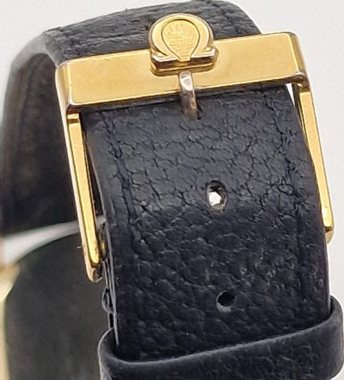 fig 2. A 1954 Omega Century wristwatch with a gold-filled circular case, patinated dial with arrow markers, sub-seconds display, and a black leather strap.