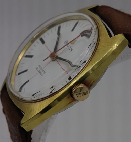 fig 2. A 1970s Bulova automatic wristwatch featuring a gold-toned cushion case, a white crosshair dial with black markers, and a brown leather strap.