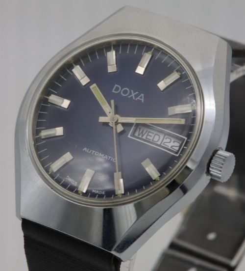 fig 1. A 1970s Doxa automatic wristwatch featuring a cushion-shaped stainless steel case, blue dial with day-date aperture, and black strap.