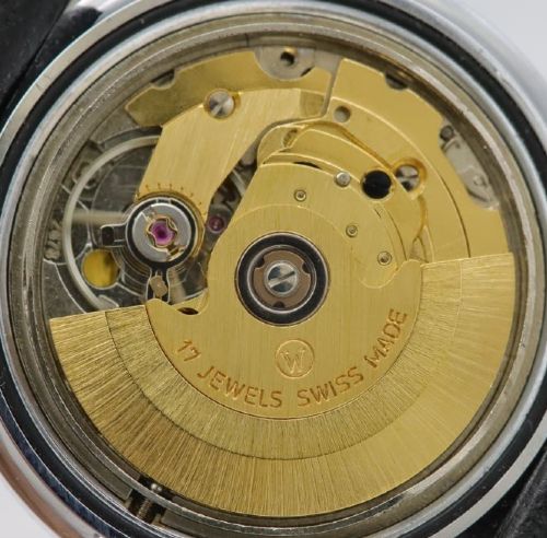 A 1970s Doxa automatic wristwatch featuring a cushion-shaped stainless steel case, blue dial with day-date aperture, and black strap. View VII