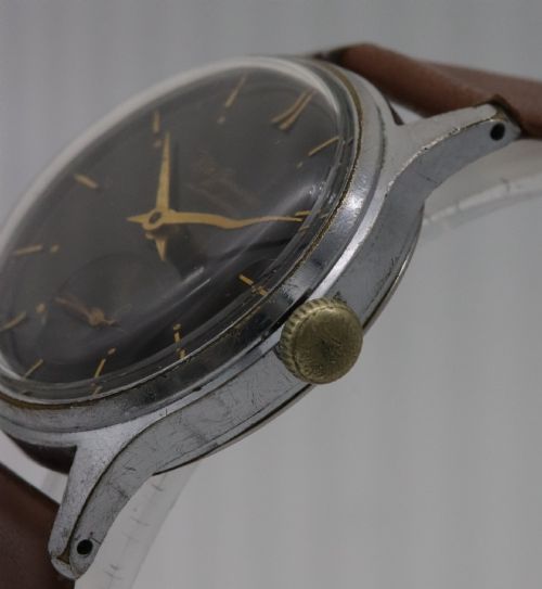 fig 2. A 1950s J.W. Benson wristwatch featuring a black dial, gold-toned hands, a sub-seconds subdial at six oclock, a metallic case, and a smooth brown leather strap.