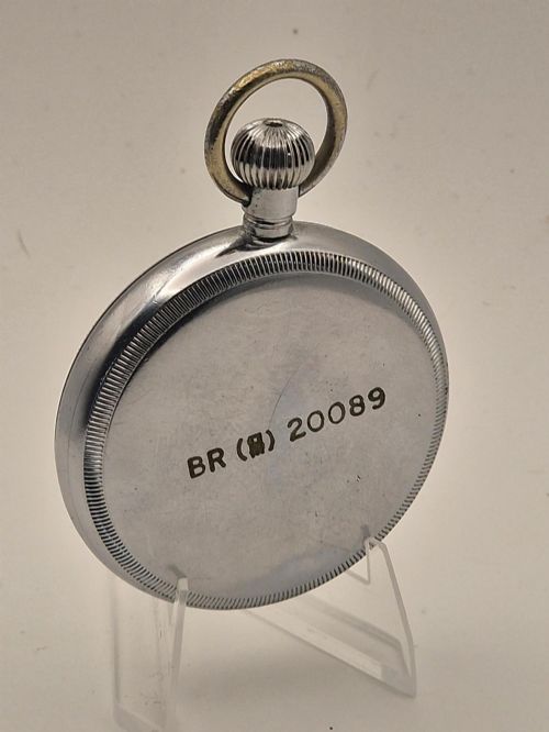 fig 1. An open-face vintage pocket watch with a silver-toned metal casing, white enamel dial displaying bold black Arabic numerals, and a small sub-seconds dial.