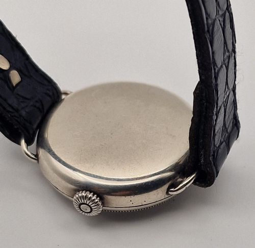 fig 1. A 1934 Omega pilot wristwatch featuring a white enamel dial with Roman numerals, an offset sub-seconds dial, blued steel hands, a coin-edge bezel, and a black leather strap.