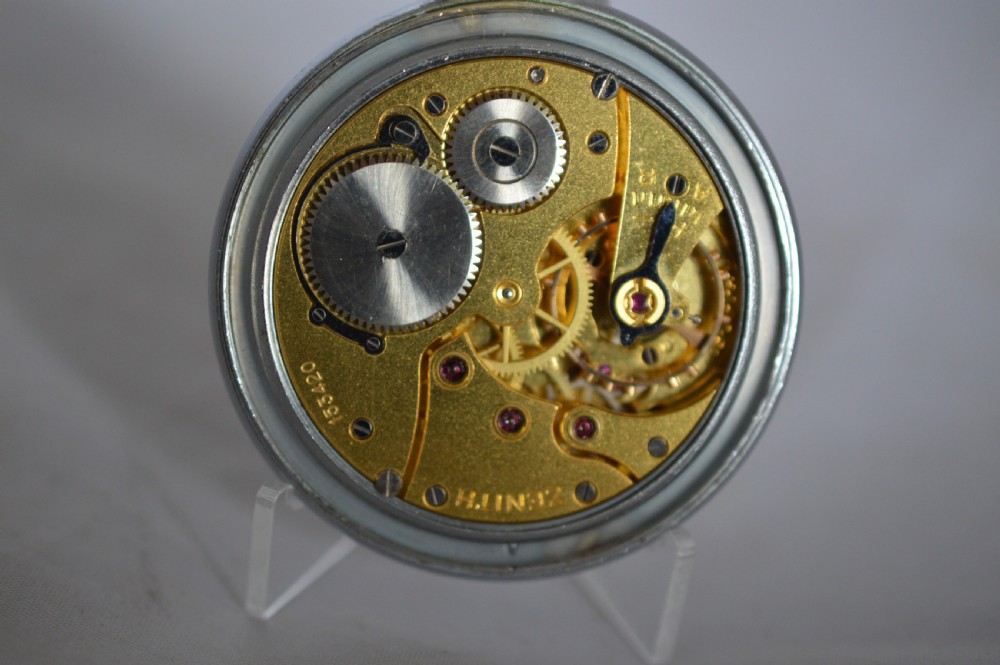 A slim silver-toned open-face Zenith pocket watch featuring a cream dial with Arabic numerals, gold-toned hands, and a small seconds sub-dial at six oclock. View V