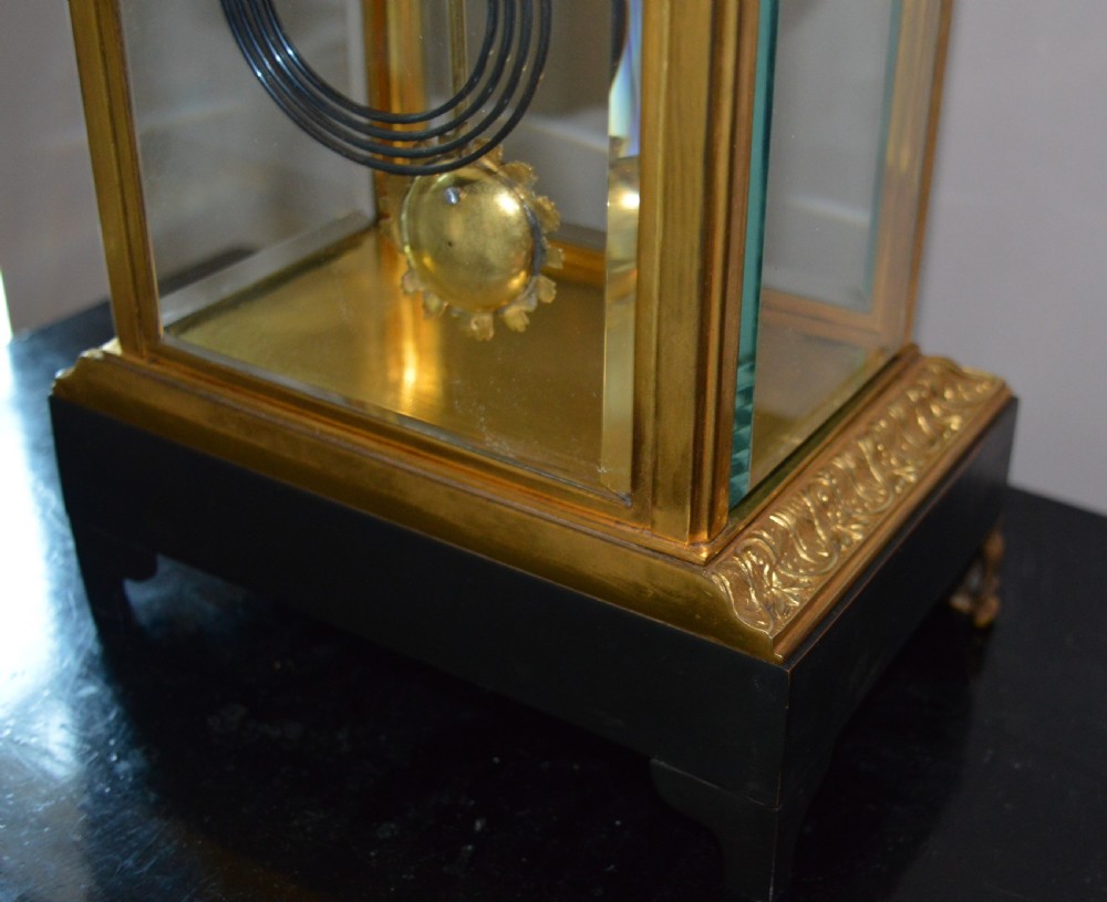A French four-glass mantel clock framed in brass and black slate flanked by two matching brass candlesticks. View II