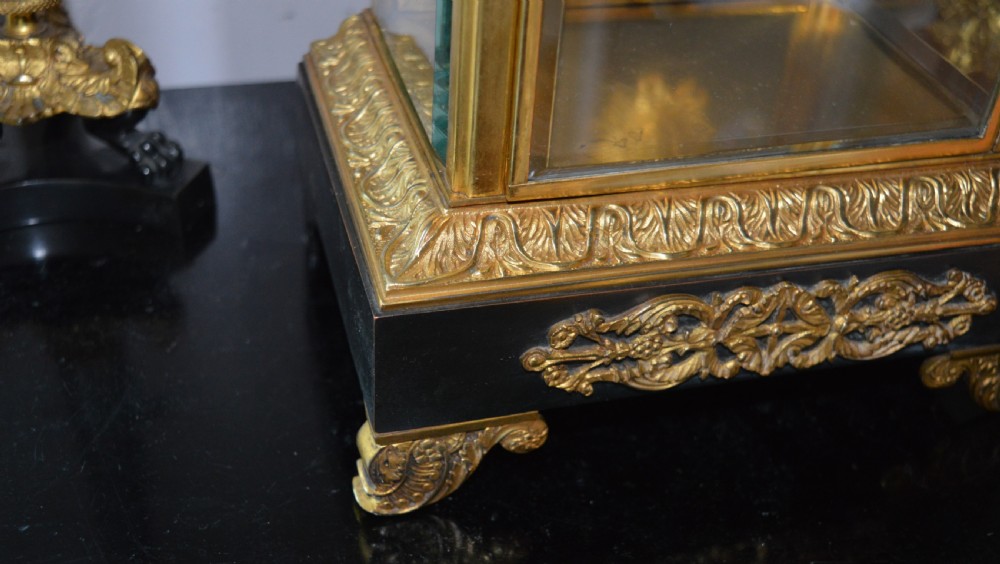 A French four-glass mantel clock framed in brass and black slate flanked by two matching brass candlesticks. View IV