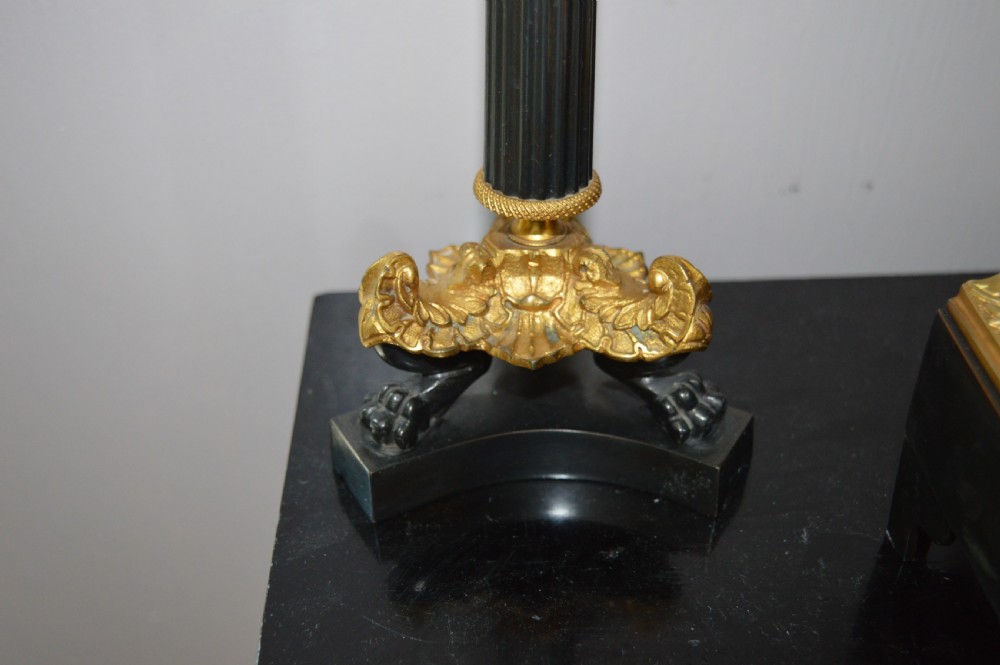 A French four-glass mantel clock framed in brass and black slate flanked by two matching brass candlesticks. View V