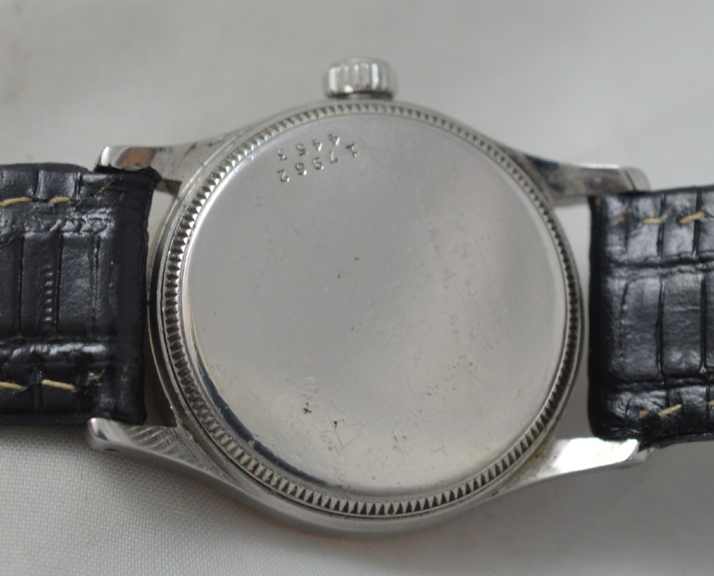 A 1940s Tudor Oyster bi-metal wristwatch featuring a cream dial with Arabic numerals, a gold bezel, a stainless steel case, and a textured black leather strap. View IV