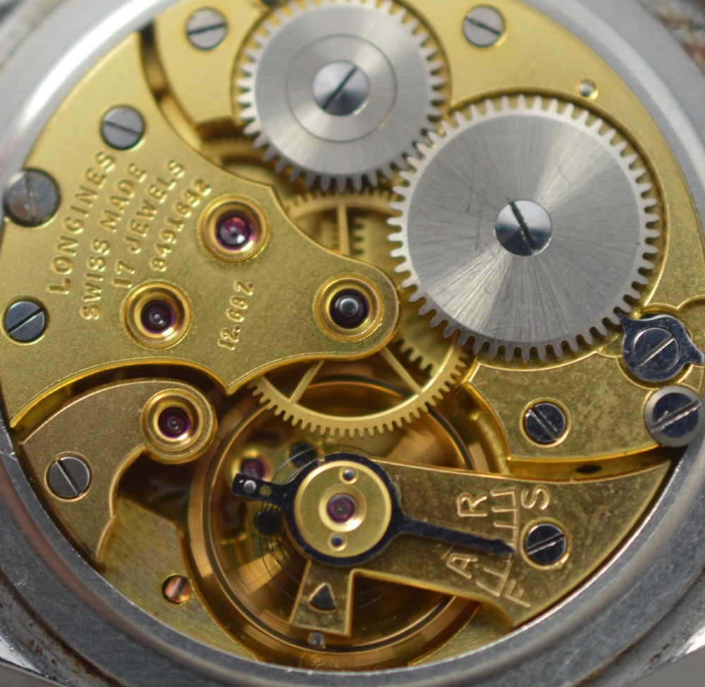 A 1951 Longines gentlemans mechanical wristwatch with a circular stainless steel case, cream dial featuring sub-seconds, and a dark brown leather strap. View V