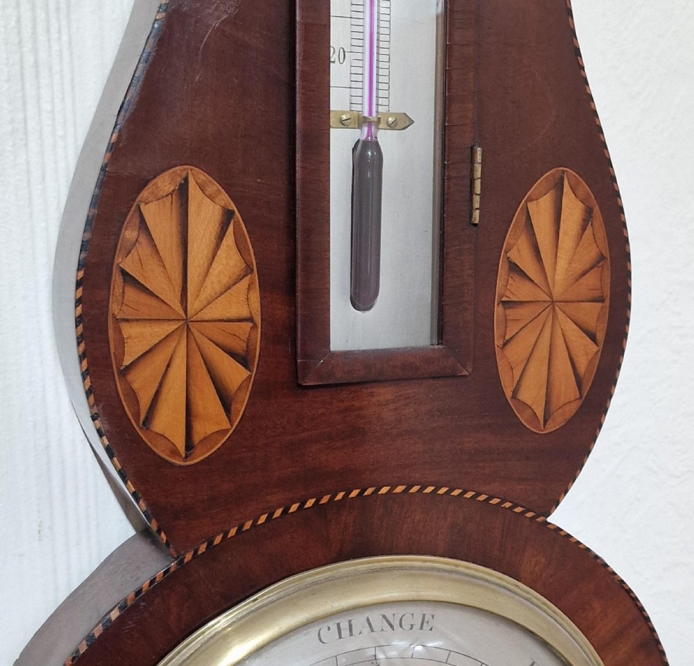 A Georgian mahogany wheel barometer featuring decorative inlaid patera motifs, an integrated thermometer tube, and a round silvered dial. View III