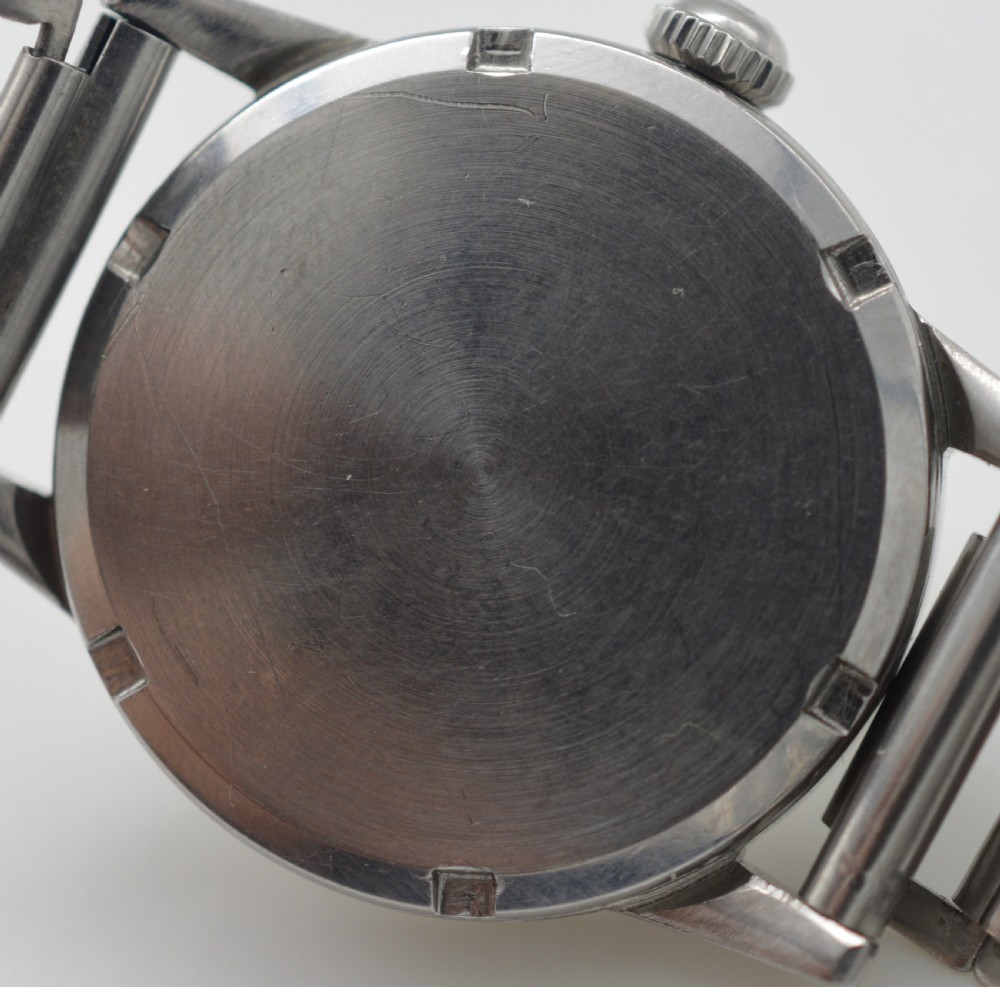 A 1944 Omega military-style wristwatch featuring a patinated cream dial, black Arabic numerals, dark hands, a stainless steel case, and a flexible metal bracelet. View V
