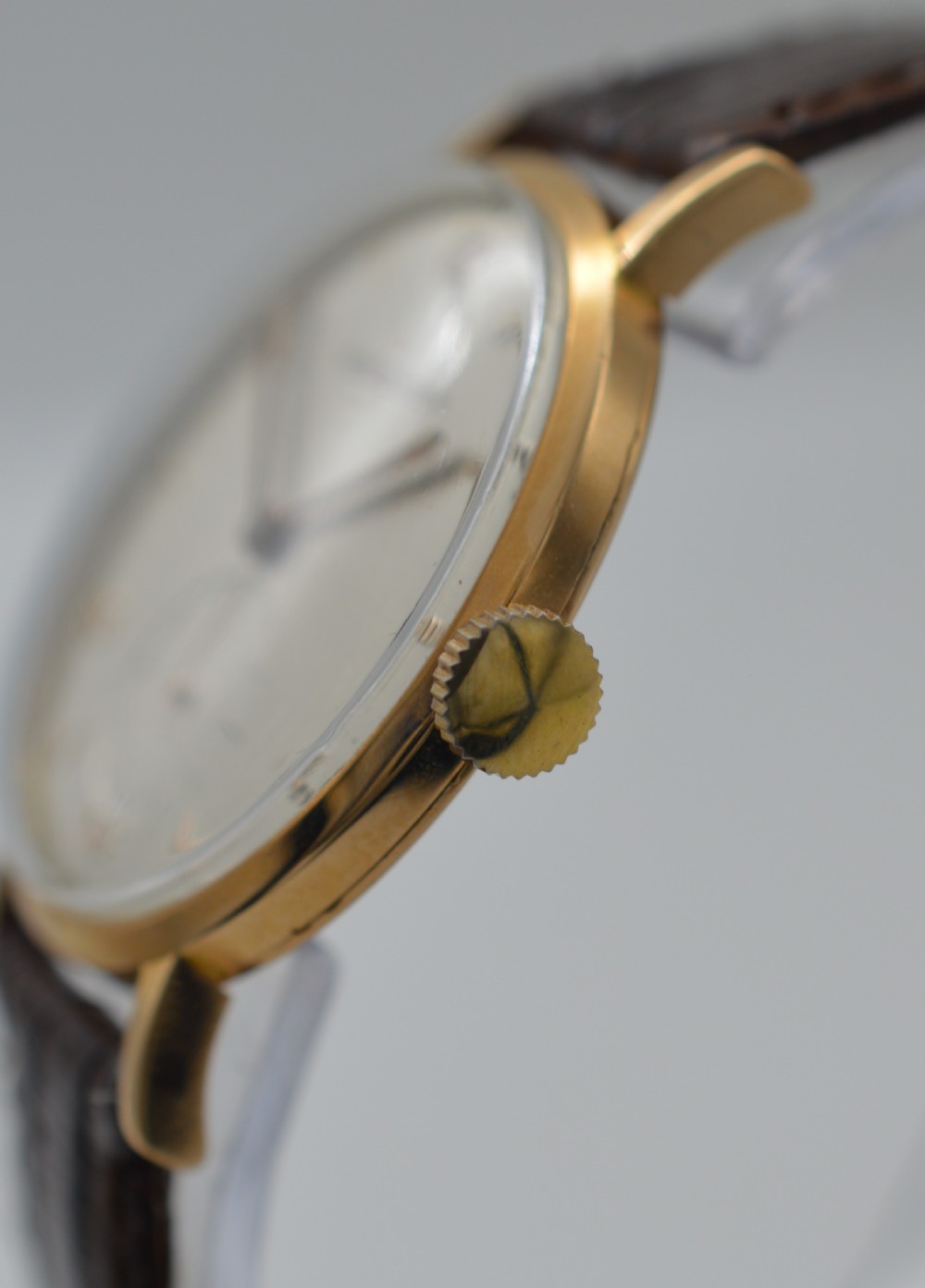 A 1950s Jaeger-LeCoultre wristwatch featuring an 18K rose gold round case, cream dial with rose gold markers, sub-seconds dial at six oclock, and brown leather strap. View II