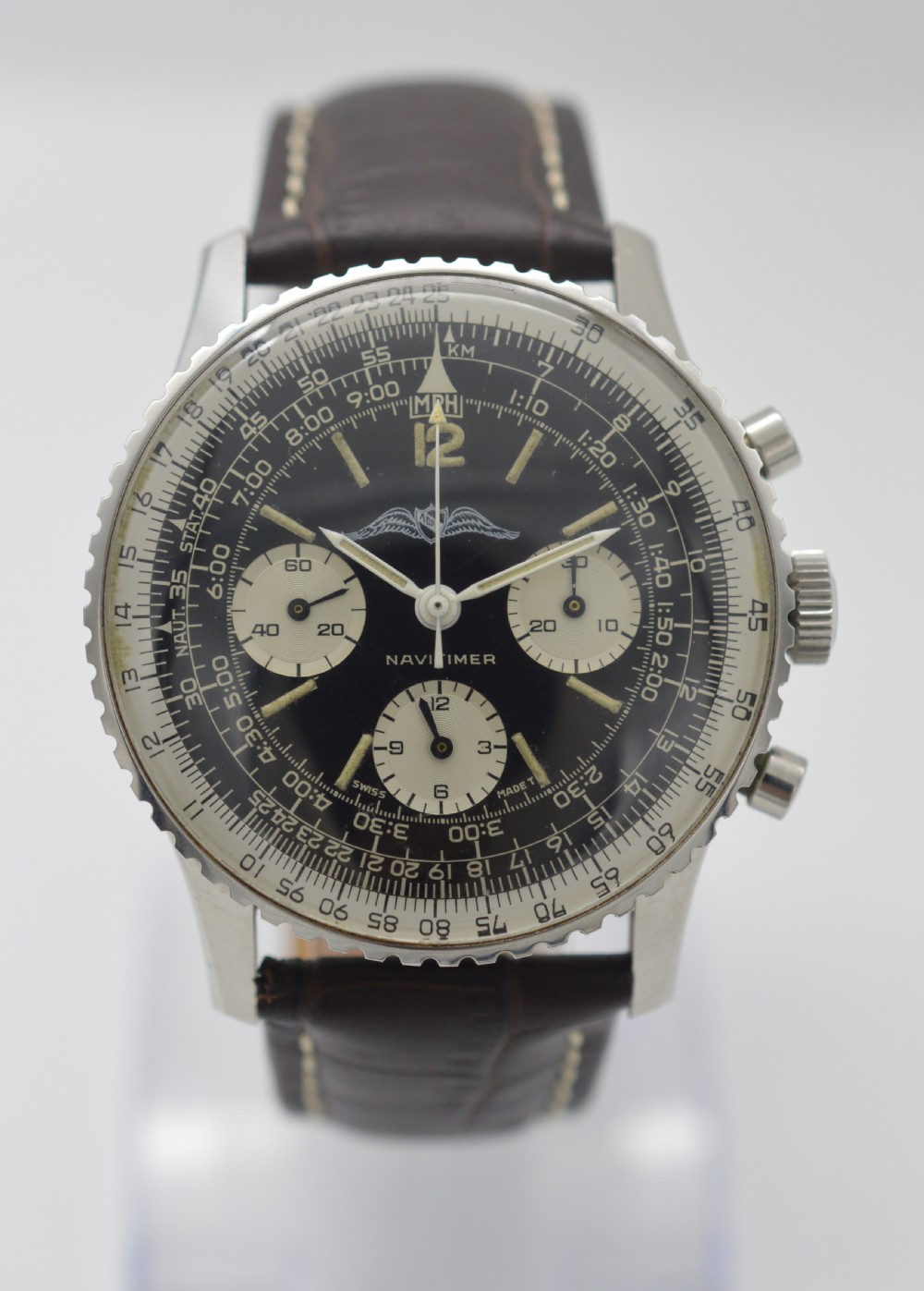 A vintage stainless steel Breitling Navitimer chronograph wristwatch featuring a black dial with white sub-dials, an AOPA wing emblem, slide rule bezel, and a brown leather strap.
