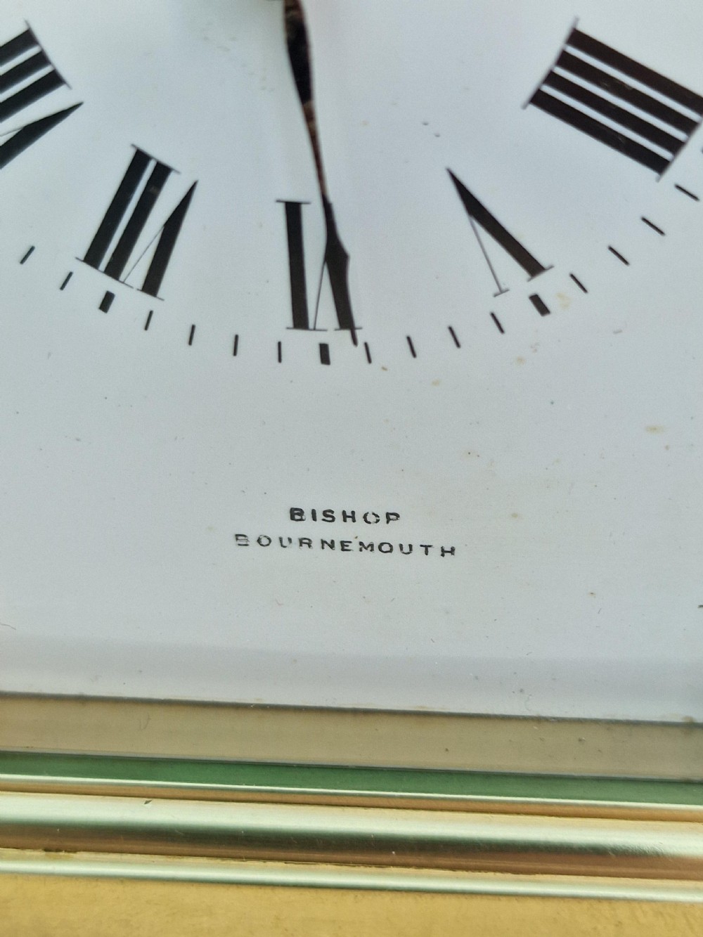 An antique brass repeating carriage clock featuring a white enamel dial with Roman numerals, bevelled glass panels, and a hinged top handle. View V
