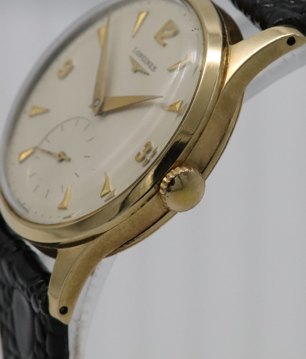 A vintage 1962 Longines wristwatch featuring a circular 9K gold case, cream dial with gold hour markers, sub-seconds dial, and a black leather strap. View III