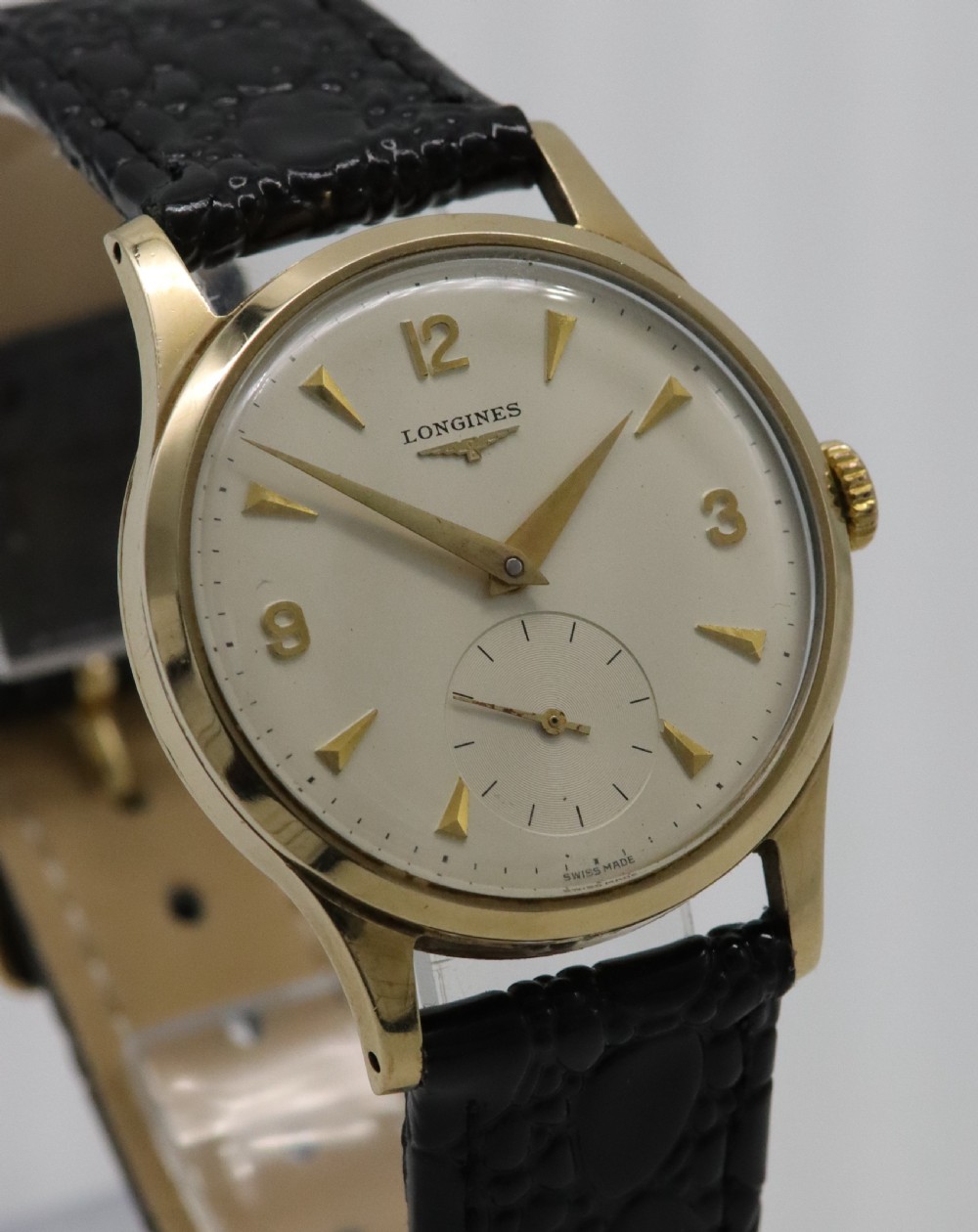 A vintage 1962 Longines wristwatch featuring a circular 9K gold case, cream dial with gold hour markers, sub-seconds dial, and a black leather strap. View IV