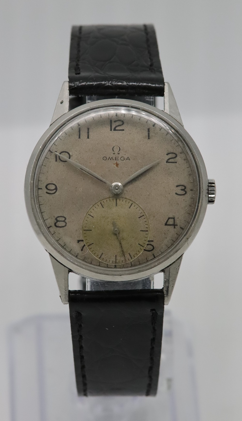 A 1944 vintage Omega Teddington wristwatch featuring a circular silver-tone dial with Arabic numerals, a sub-seconds register, a small red star emblem, and a black leather strap.