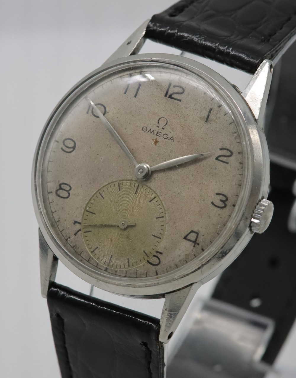 A 1944 vintage Omega Teddington wristwatch featuring a circular silver-tone dial with Arabic numerals, a sub-seconds register, a small red star emblem, and a black leather strap. View II