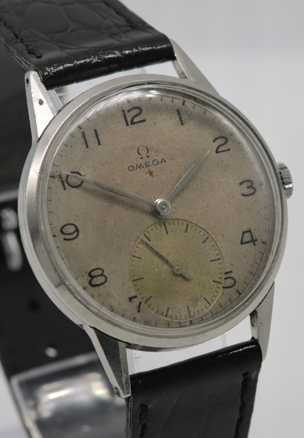 A 1944 vintage Omega Teddington wristwatch featuring a circular silver-tone dial with Arabic numerals, a sub-seconds register, a small red star emblem, and a black leather strap. View IV