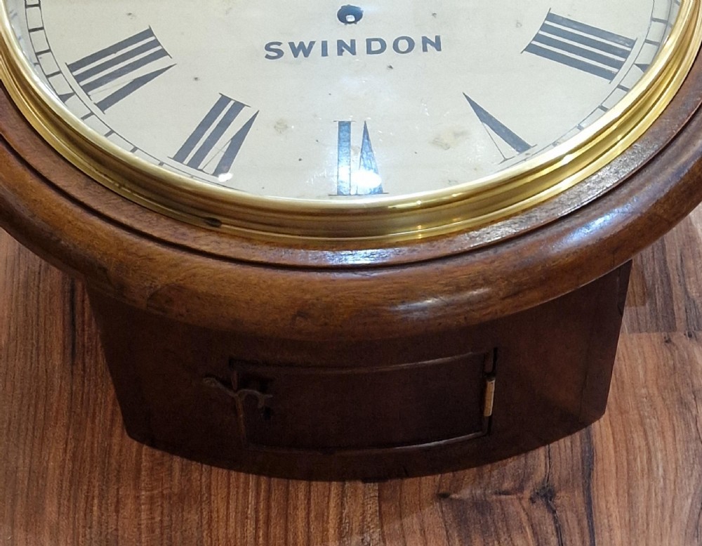 A circular Victorian mahogany fusee dial wall clock featuring a white face with Roman numerals, a brass bezel, and black spade hands, marked Rudge Swindon. View II