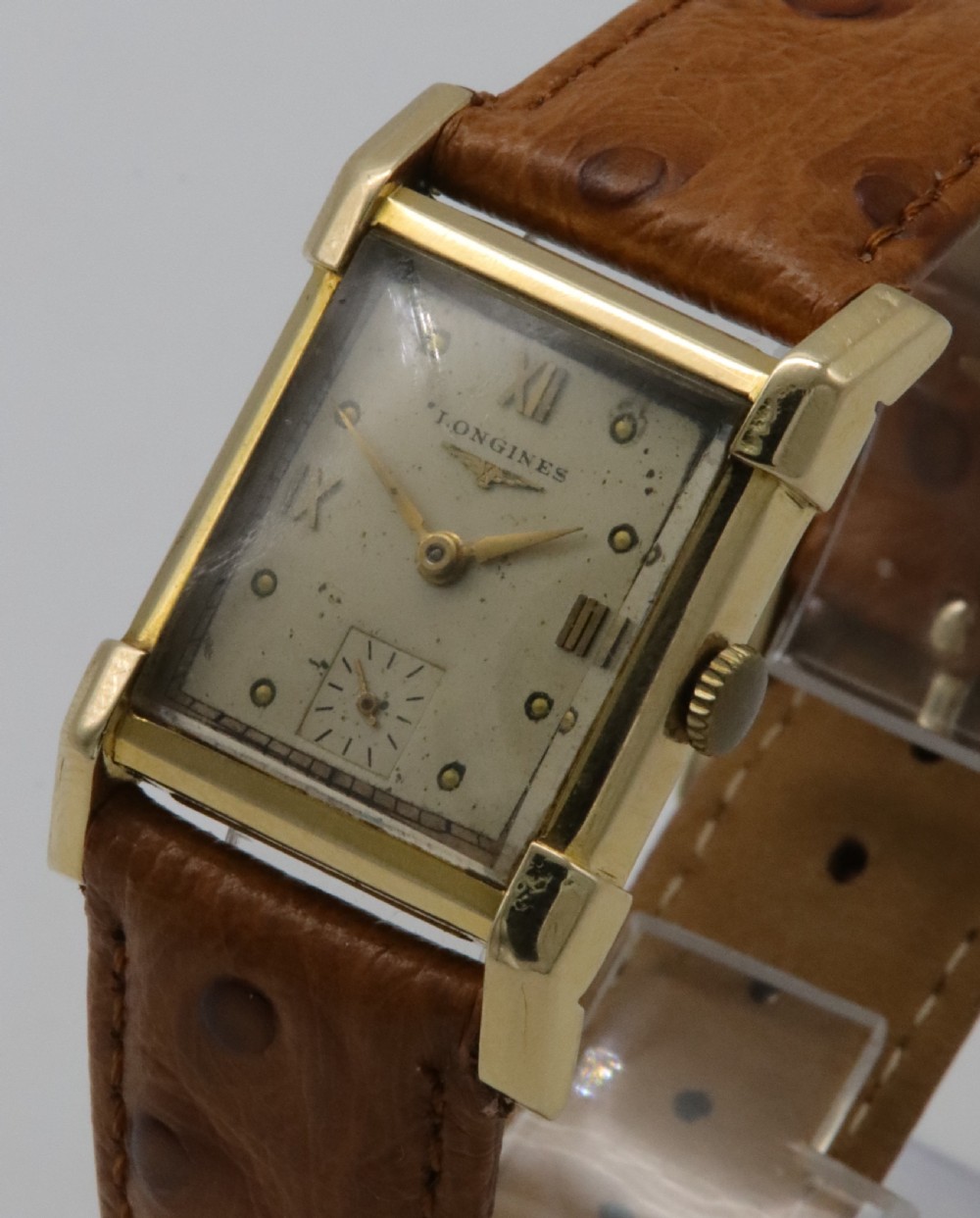 A 1949 Longines rectangular 14k gold wristwatch featuring a cream dial with sub-seconds register and a tan leather strap. View II