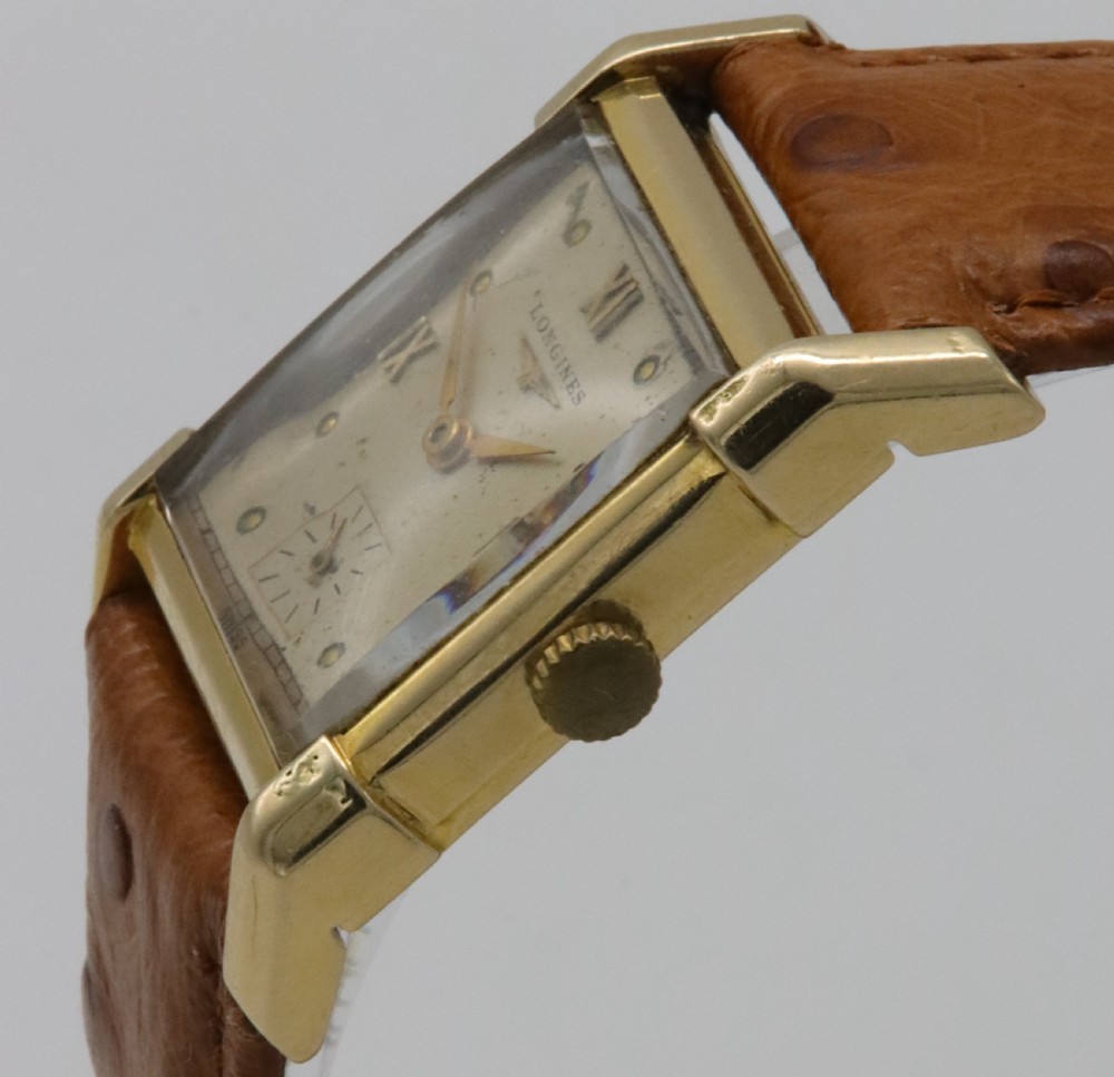 A 1949 Longines rectangular 14k gold wristwatch featuring a cream dial with sub-seconds register and a tan leather strap. View VII