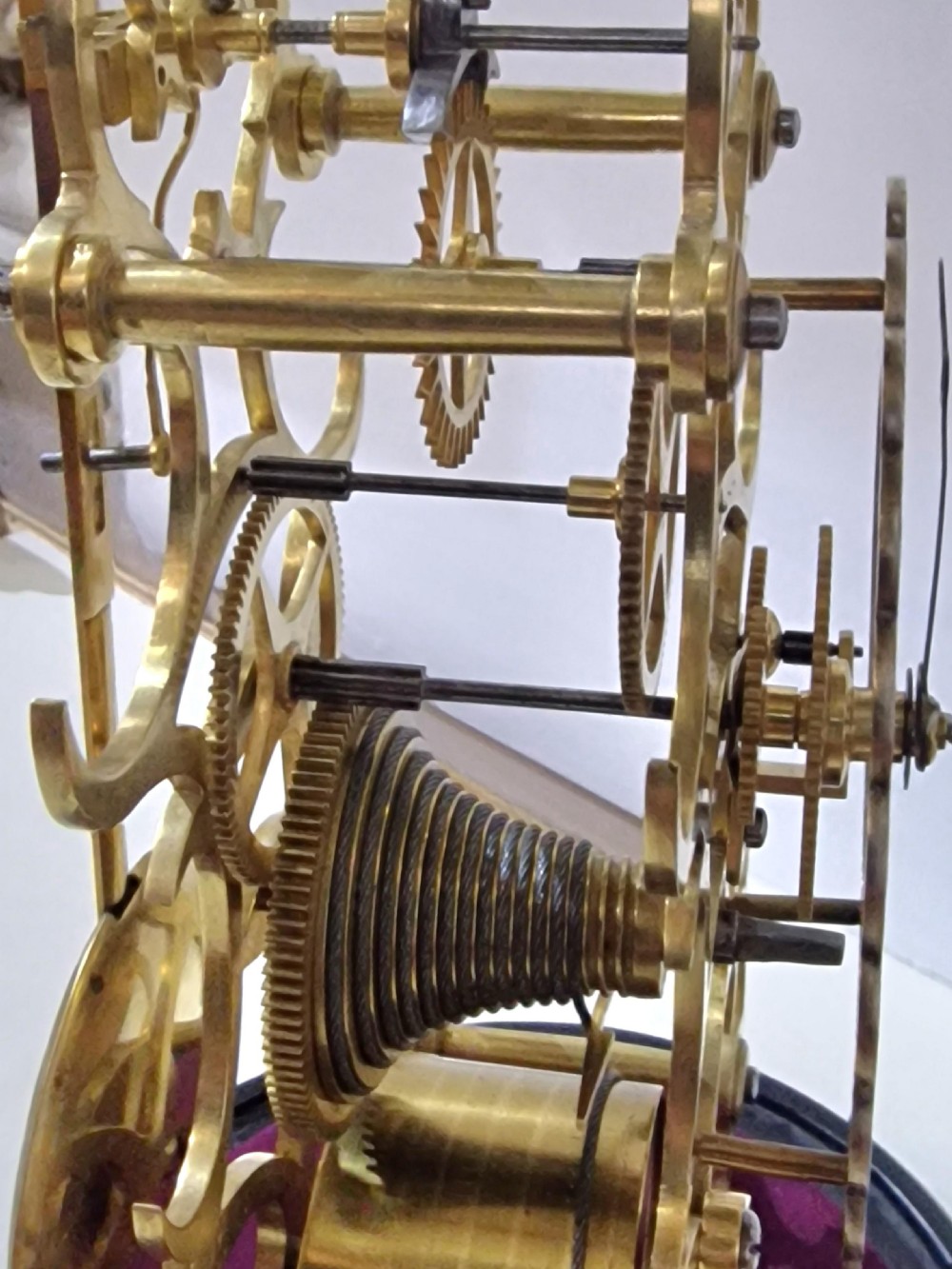 A Victorian brass skeleton clock with an exposed movement and silvered chapter ring, displayed beneath a clear glass dome on an ebonised base. View V