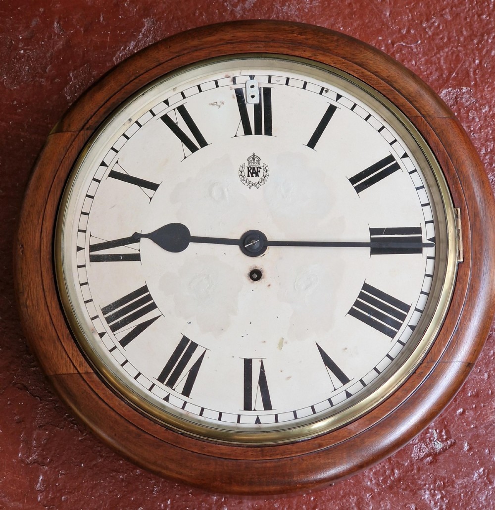 A circular mahogany wall clock featuring a brass bezel around an off-white dial with black Roman numerals and an RAF insignia.