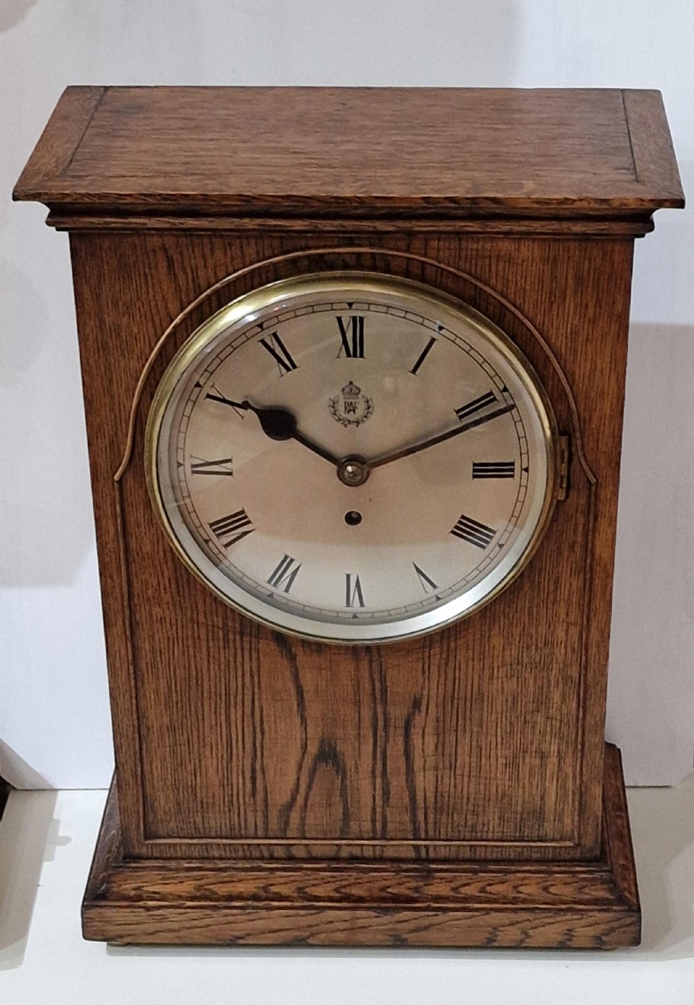 A Second World War period oak RAF officers mess mantel clock featuring a white dial with Roman numerals and Royal Air Force crest.