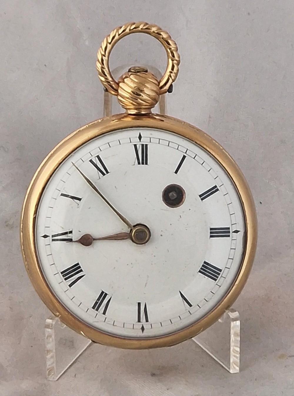 A Georgian gilt verge fusee pocket watch featuring a white enamel dial with Roman numerals and a textured twisted suspension loop.