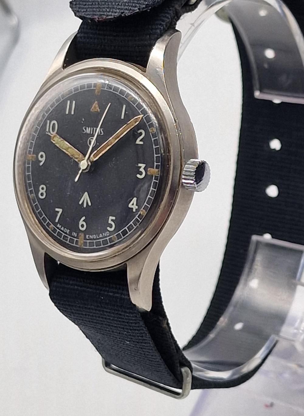 A Smiths W10 military wristwatch featuring a black dial with Arabic numerals, broad arrow mark, and a black strap. View V
