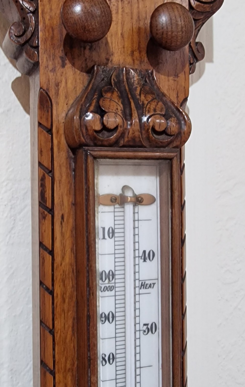 A carved Victorian oak stick barometer featuring an exposed mercury tube, dual weather scales, integrated thermometer, and a carved foliate cistern cover. View IV