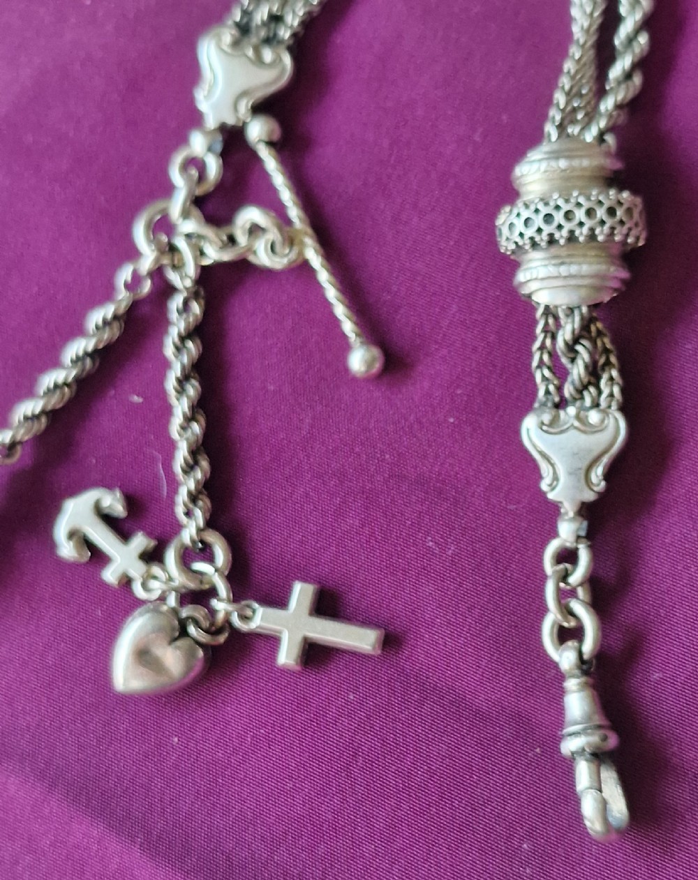 An antique silver chatelaine pocket watch chain featuring multi-strand braided rope links, a decorative slide barrel, a wire tassel, and suspended faith, hope, and charity charms. View II
